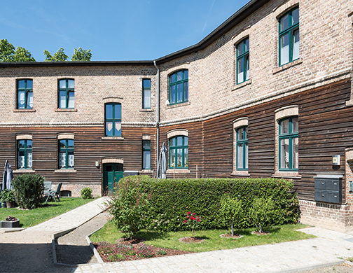 Mehrfamilienhaus in Schenkendorf (Königs Wusterhausen), teils Holzfassade, viel Grün vor dem Haus