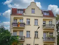 Wohn- und Geschäftshaus in Berlin-Lichtenberg, mit Balkonen und gelber Außenfassade