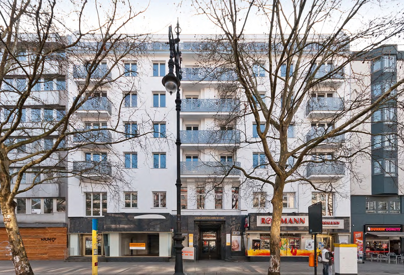 Wohn- und Geschäftshaus in Berlin Charlottenburg-Wilmersdorf, helle Außenfassade mit Balkonen und Bäumen vor dem Haus