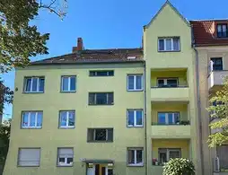Mehrfamilienhaus in Berlin-Lichtenberg mit gelber Außenfassade und Balkonen