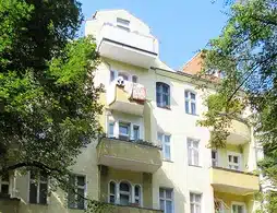 Wohn- und Geschäftshaus in Berlin-Neukölln, gelbe Außenfassade mit Balkonen